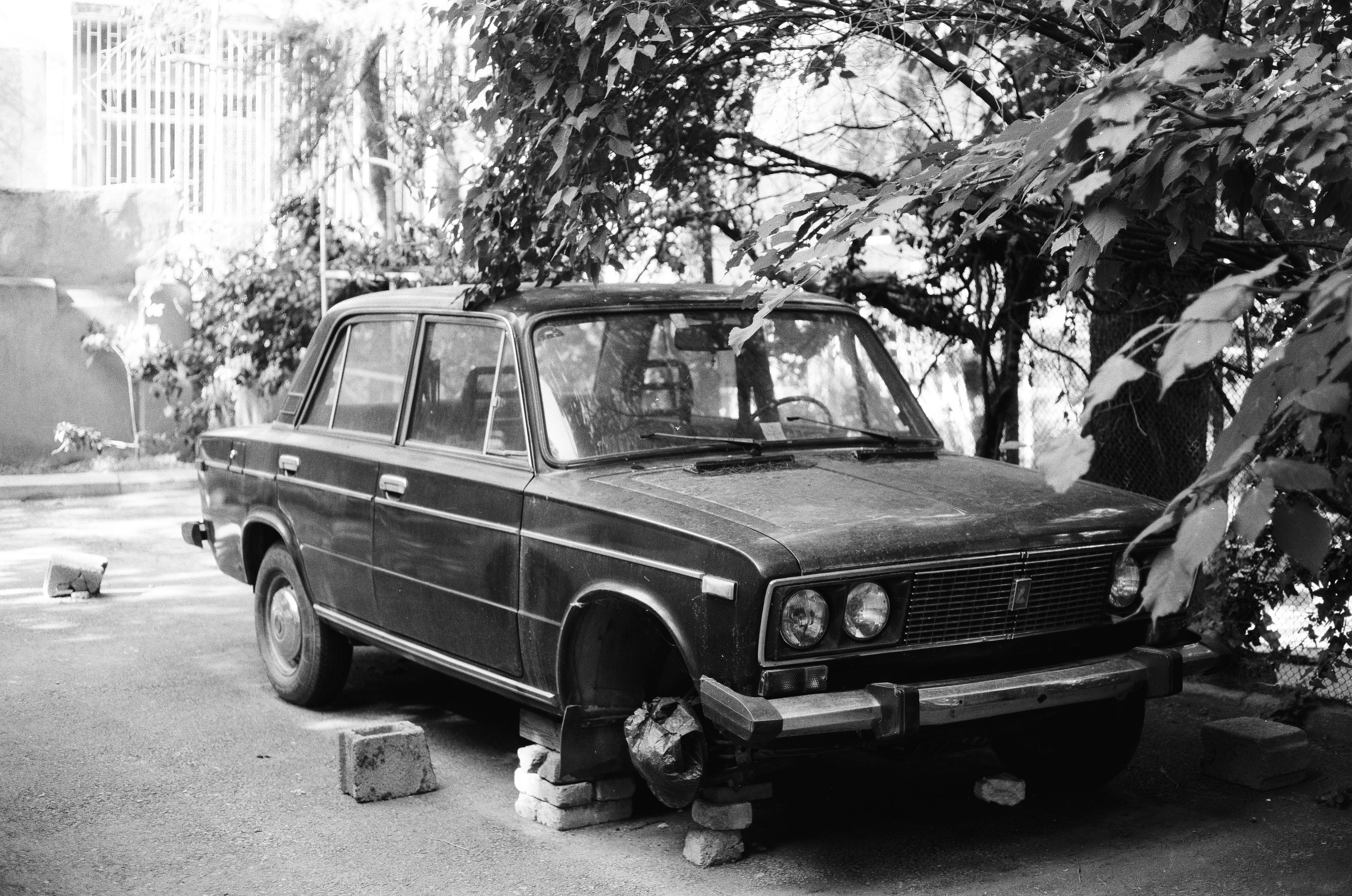 grayscale photo of man standing beside vintage car